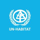 UN-Habitat logo featuring a white emblem with a triangle and house symbol, encircled by olive branches, on a blue background.