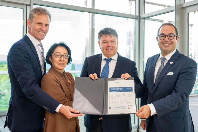 A group of people holding a document in front of a window.