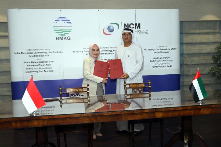 Two people standing in front of a table signing a document.