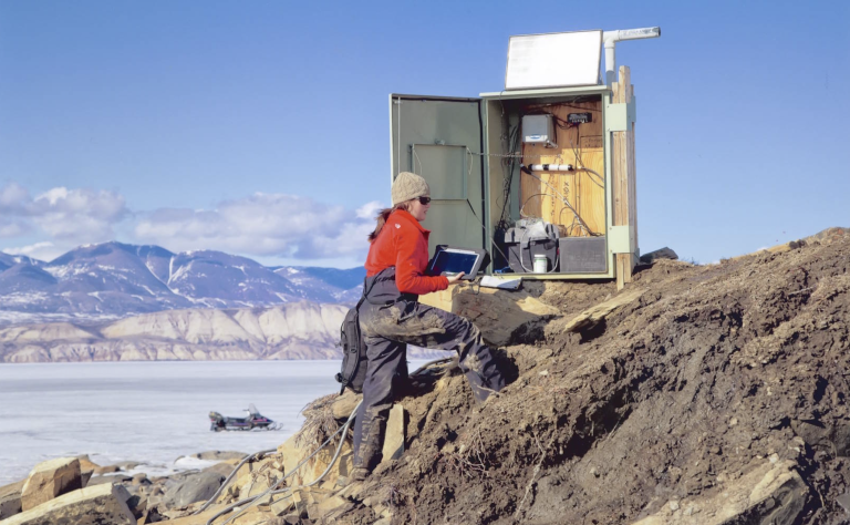 A man standing on top of a mountain with a laptop computer.