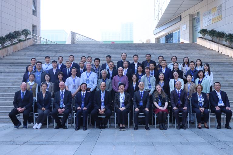 A diverse group of professionals pose for a group photo on outdoor stairs in front of a building