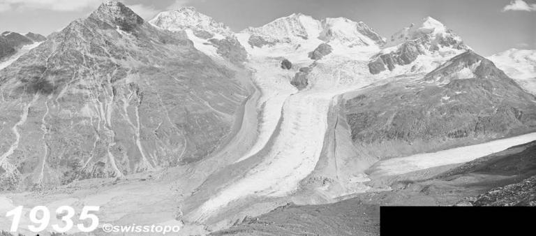 Black and white photo of a glacier in a mountain valley, surrounded by rugged peaks. The image is dated 1935.