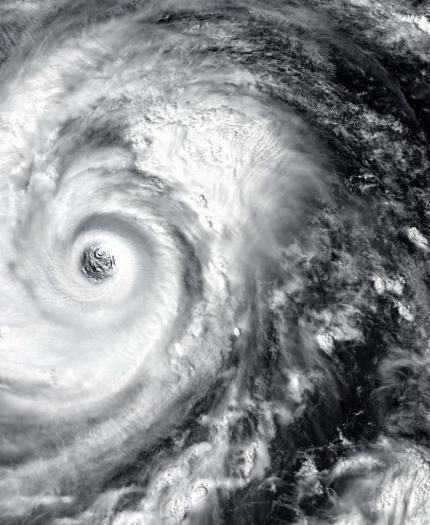 Satellite image of a swirling hurricane with a distinct eye at the center, surrounded by dense cloud formations.