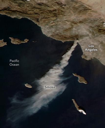 Satellite image showing smoke from wildfires near Los Angeles drifting over the Pacific Ocean. Land features and labels for Los Angeles and Pacific Ocean are visible.