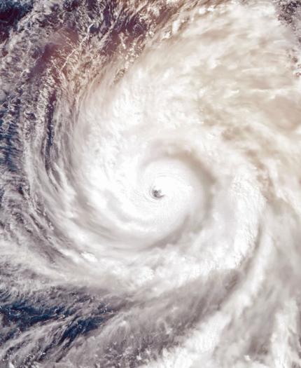 Satellite view of a swirling hurricane over the ocean, showing a distinct eye at the center surrounded by clouds.